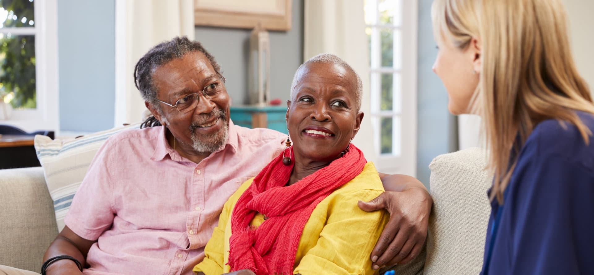 caregiver talking with senior couple smiling
