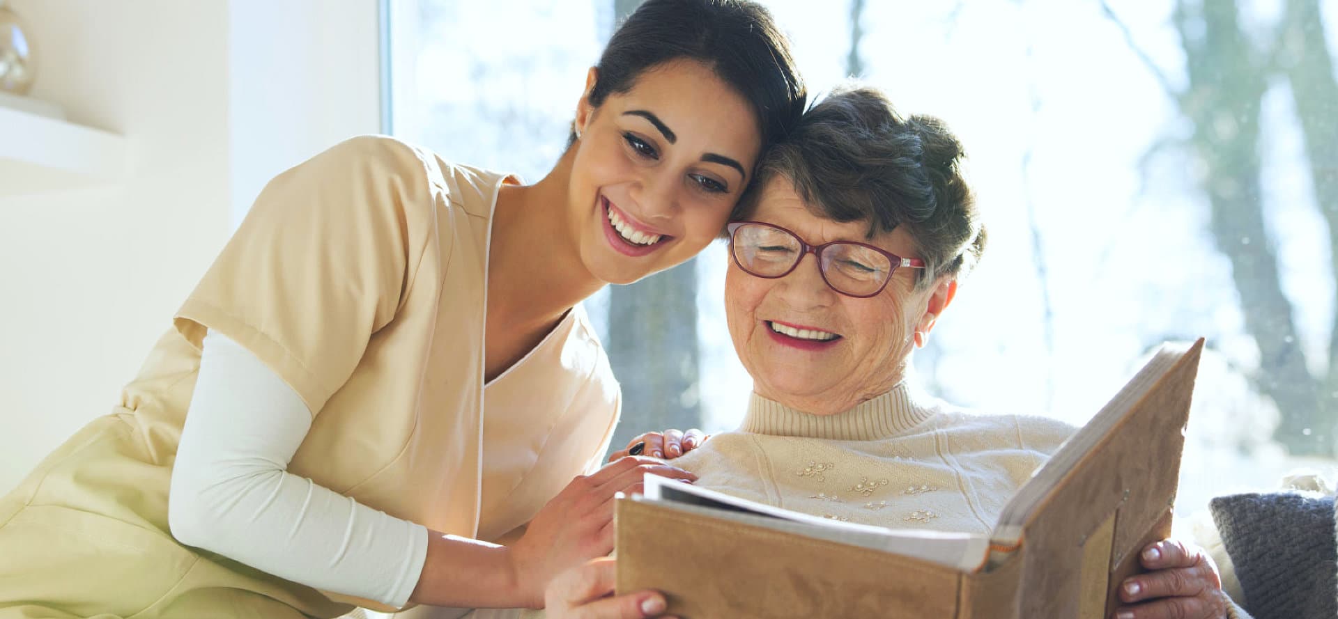 caregiver and senior womnan wearing eyeglasses smiling