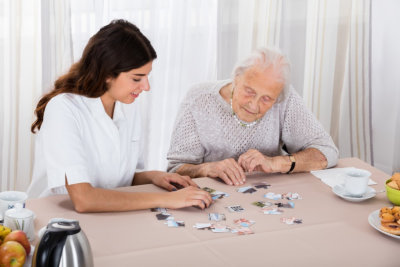 senior woman playing jigsaw puzzles on the table with her caregiver