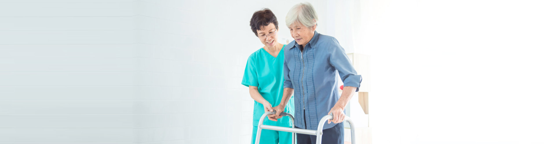 caregiver assisting senior woman walking using her walking frame