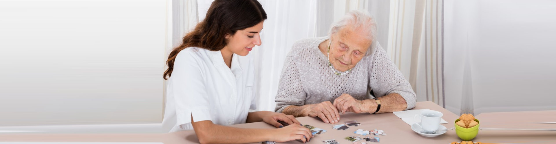 "senior woman playing jigsaw puzzles on the table with her caregiver